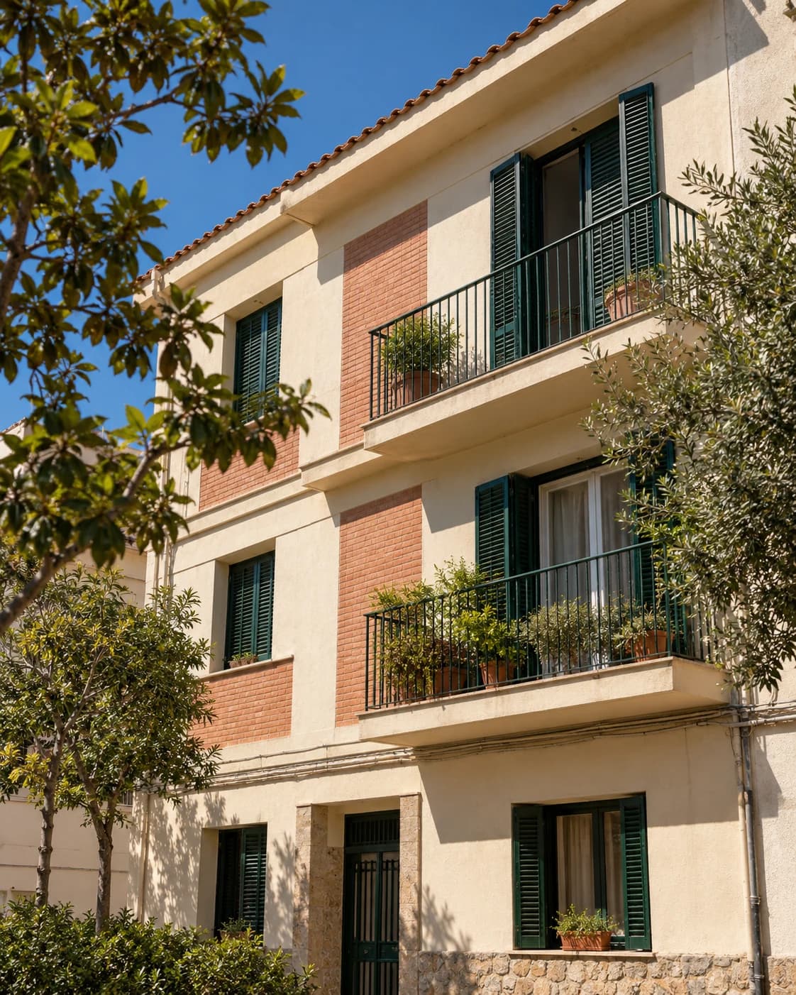 Fachada de un edificio mediterráneo con balcones y persianas verdes